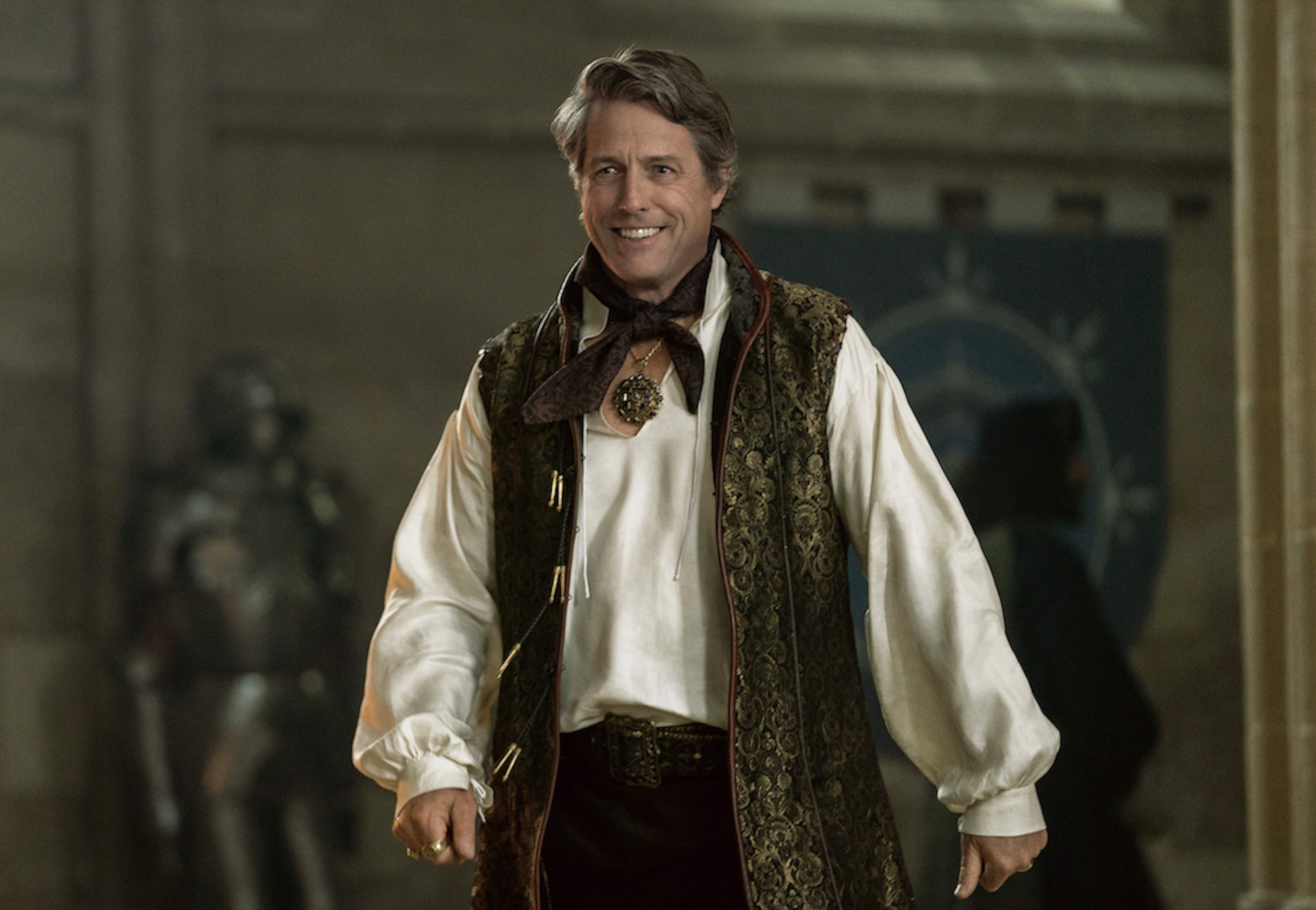 Hugh Grant smiling in ornate costume as Forge Fitzwilliam in Dungeons &amp; Dragons: Honor Among Thieves.