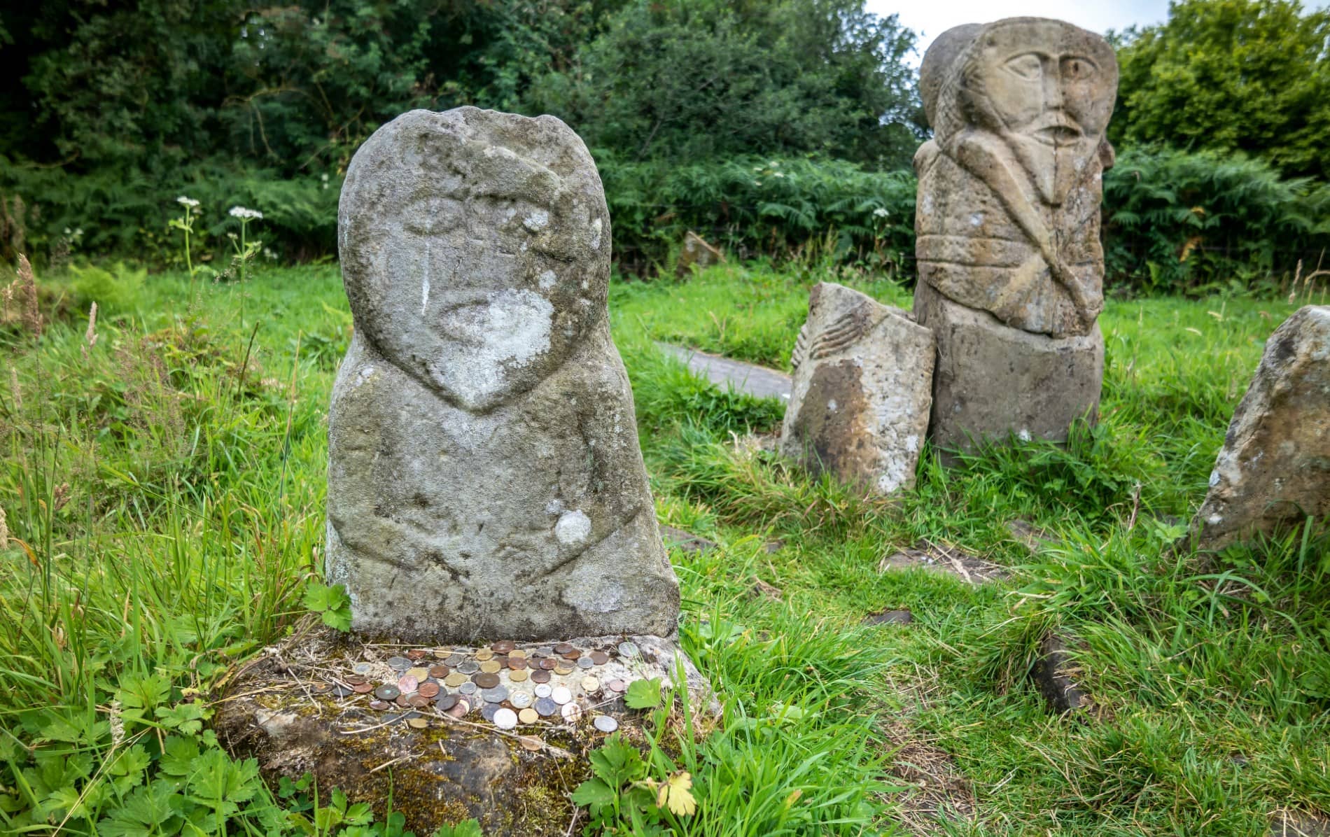 Celtic carved stone figures with offerings at Caldragh graveyard on Boa Island in County Fermanagh.