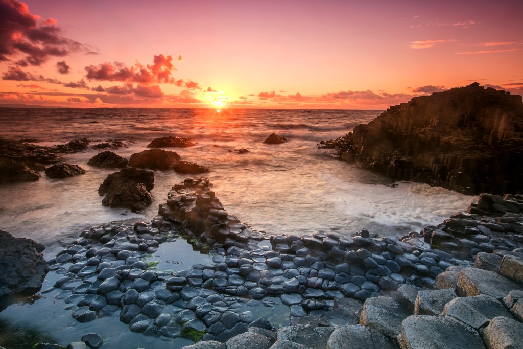 Sunset over Giant’s Causeway, County Antrim, with golden light on basalt columns and Atlantic waves.