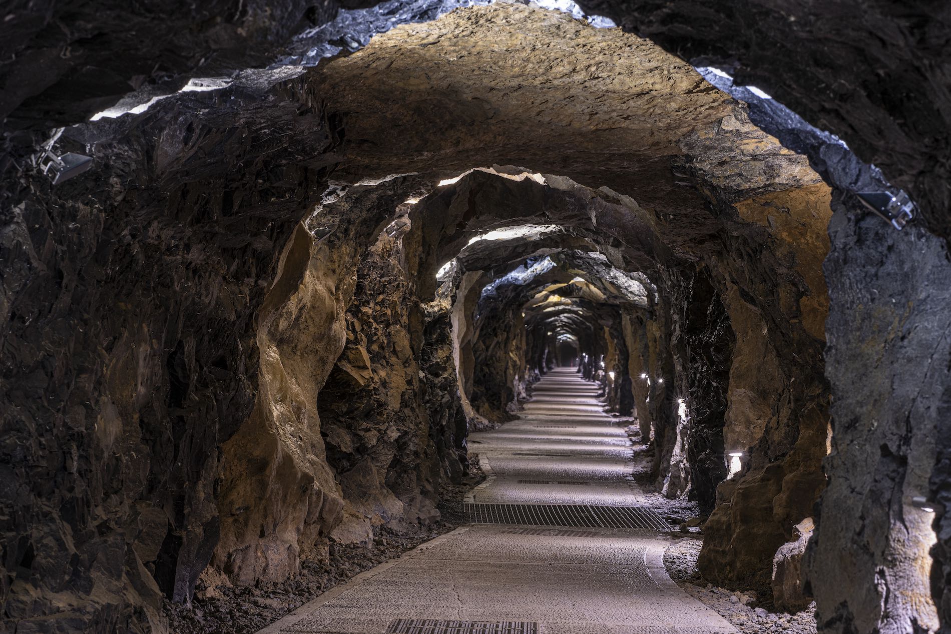 Illuminated tunnel inside Aillwee Caves, County Clare, showing rugged rock walls and a winding walkway.
