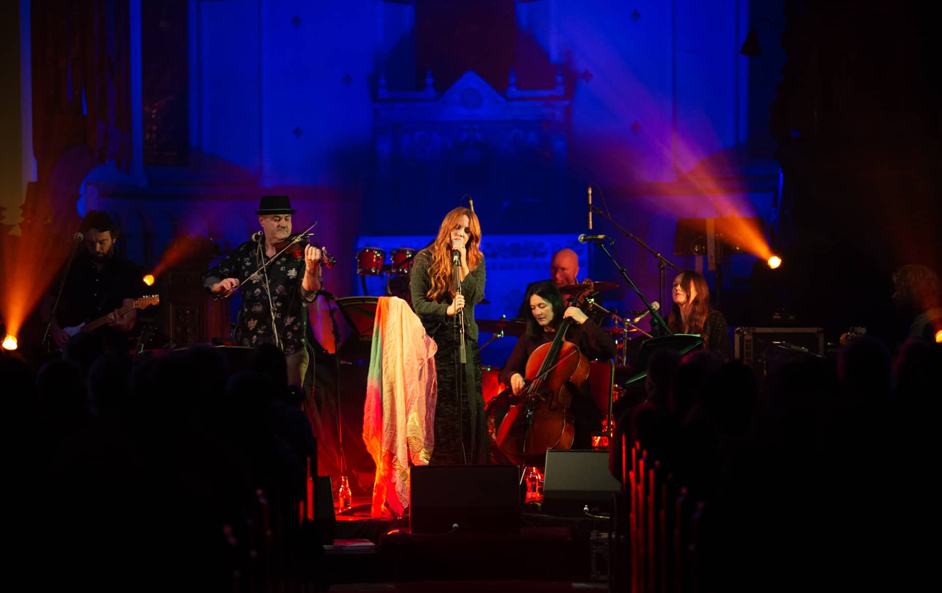 Female singer and musicians perform on stage under vibrant blue and orange lighting at TradFest in Temple Bar, Dublin.