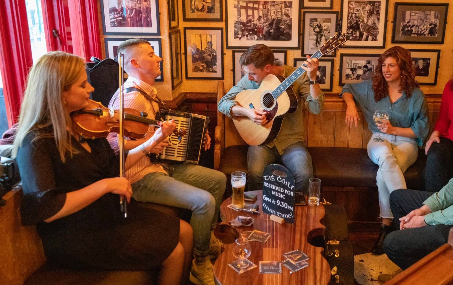 Trad musicians play fiddle, accordion and guitar at Tigh Cóilí pub, Galway, as patrons enjoy the session.