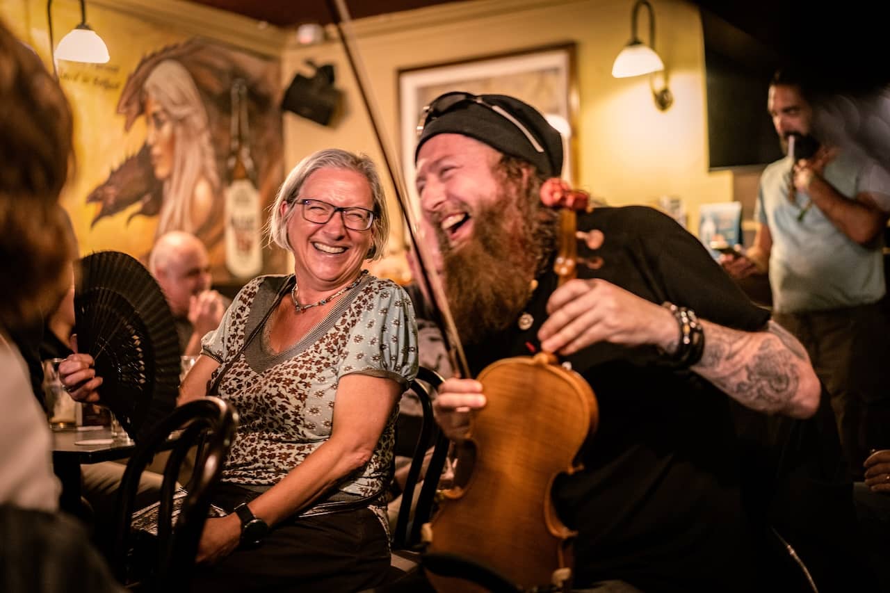 Traditional musician entertaining visitors during a lively Irish music session in McHugh's pub, Belfast.