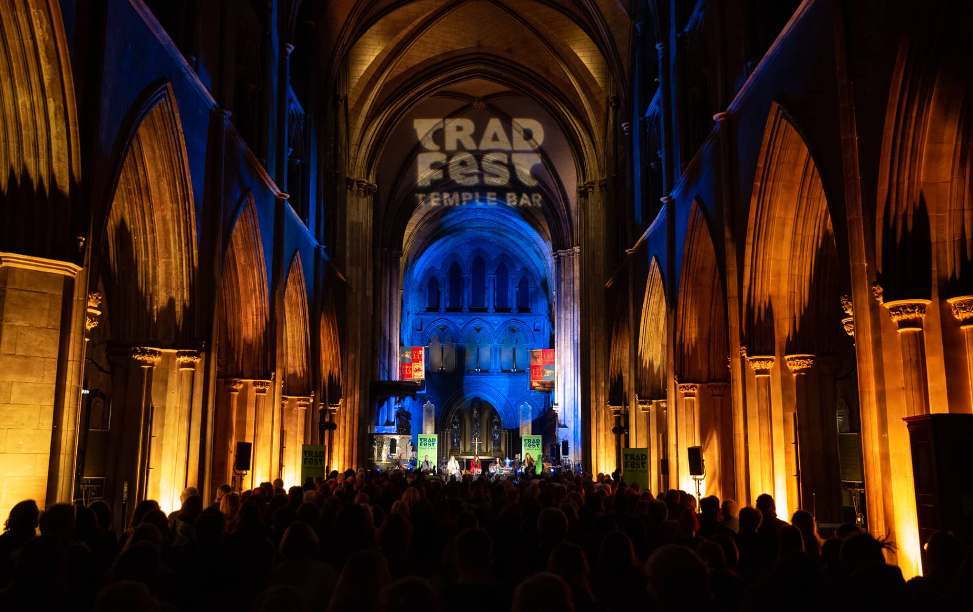 Crowd watching a TradFest concert in a cathedral-style venue lit in blue and orange in Dublin’s Temple Bar.