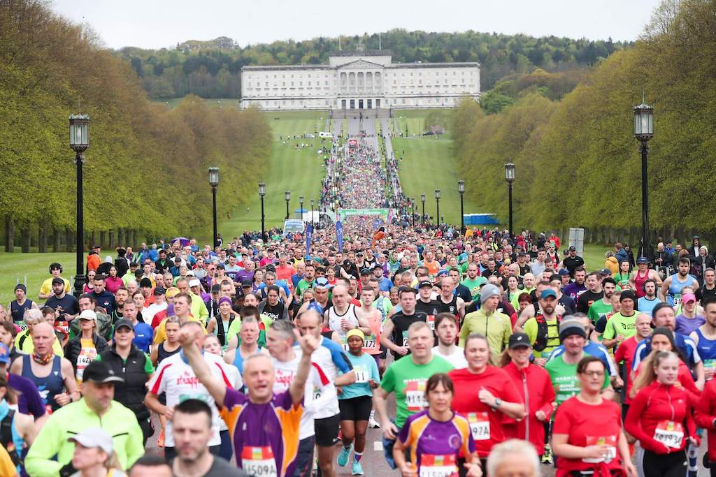 Thousands of runners in colourful athletic gear fill Prince of Wales Avenue at Stormont Estate during the Belfast City Marathon.