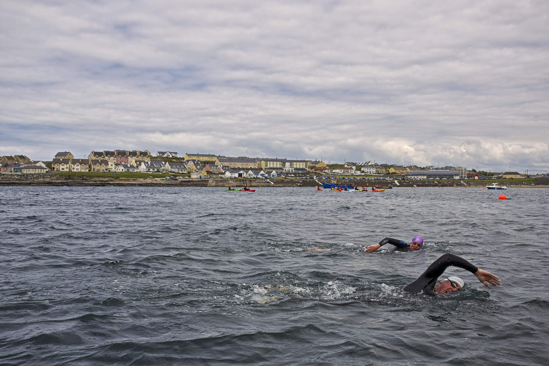 Swimmers in wetsuits and brightly coloured swim caps take part in an open water event off the coast of Lahinch, County Clare.