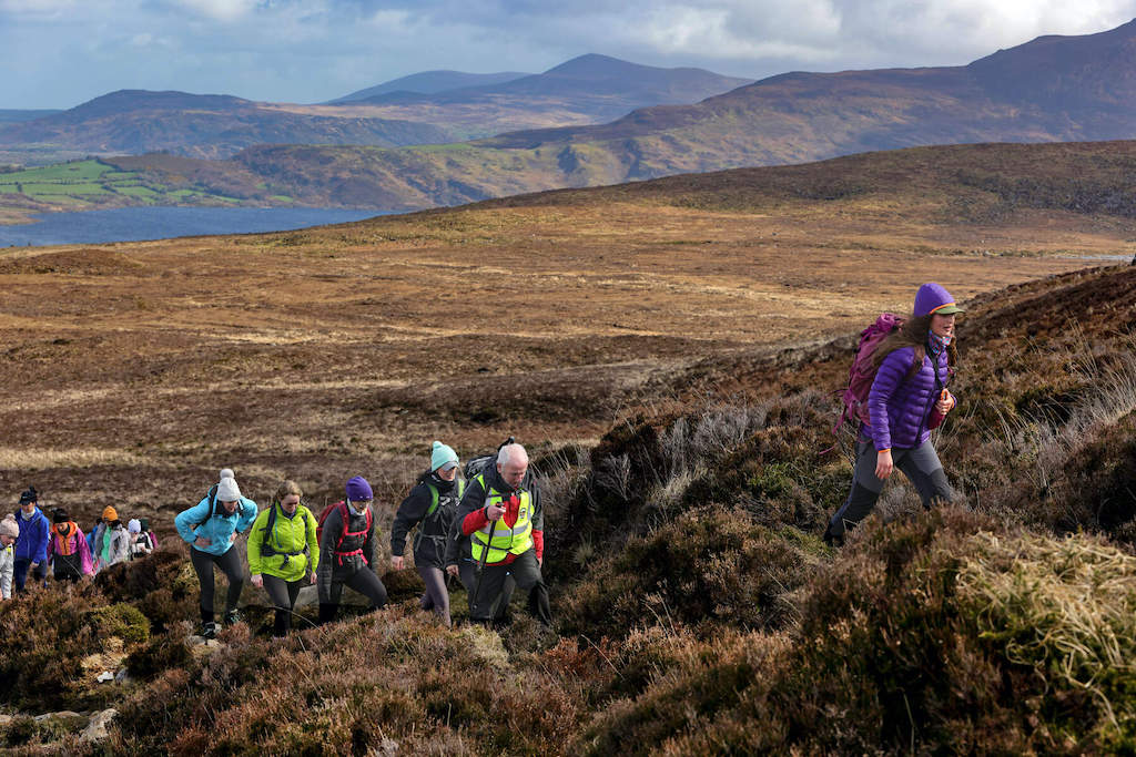 Group of hikers in outdoor gear on a heather-covered slope in the MacGillycuddy’s Reeks in Kerry.