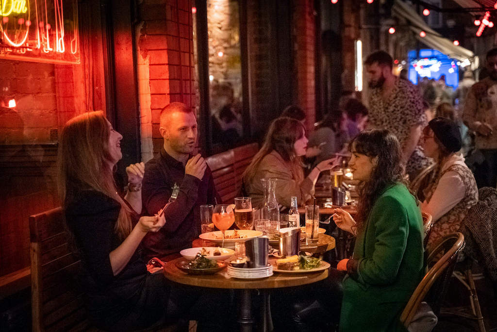 People enjoying dinner and conversation at outdoor tables under warm lighting at L’Gueuleton on Fade Street, Dublin.