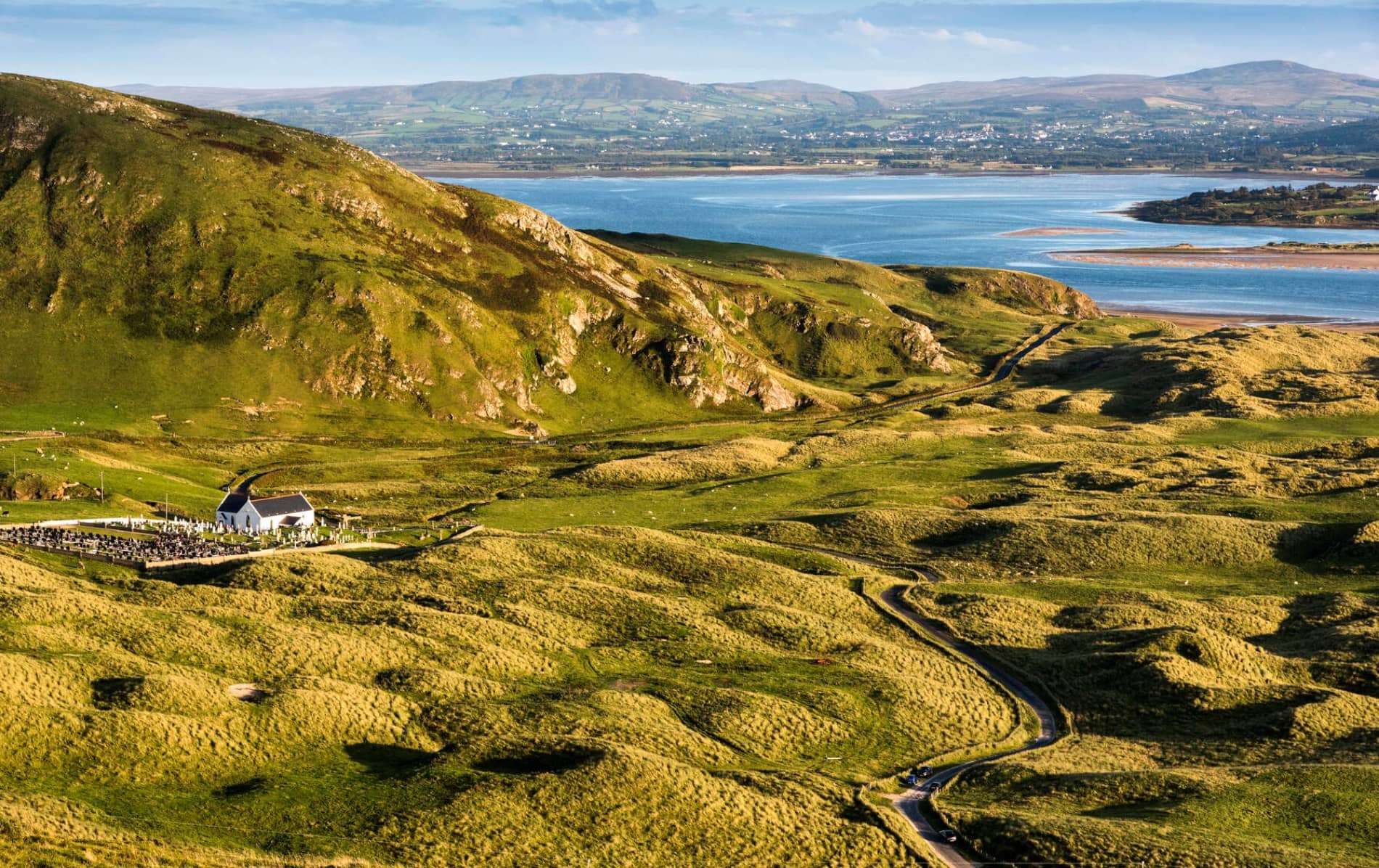 Overhead view of Five Fingers Strand, Donegal, with golden dunes, green hills and beach meeting the sea.