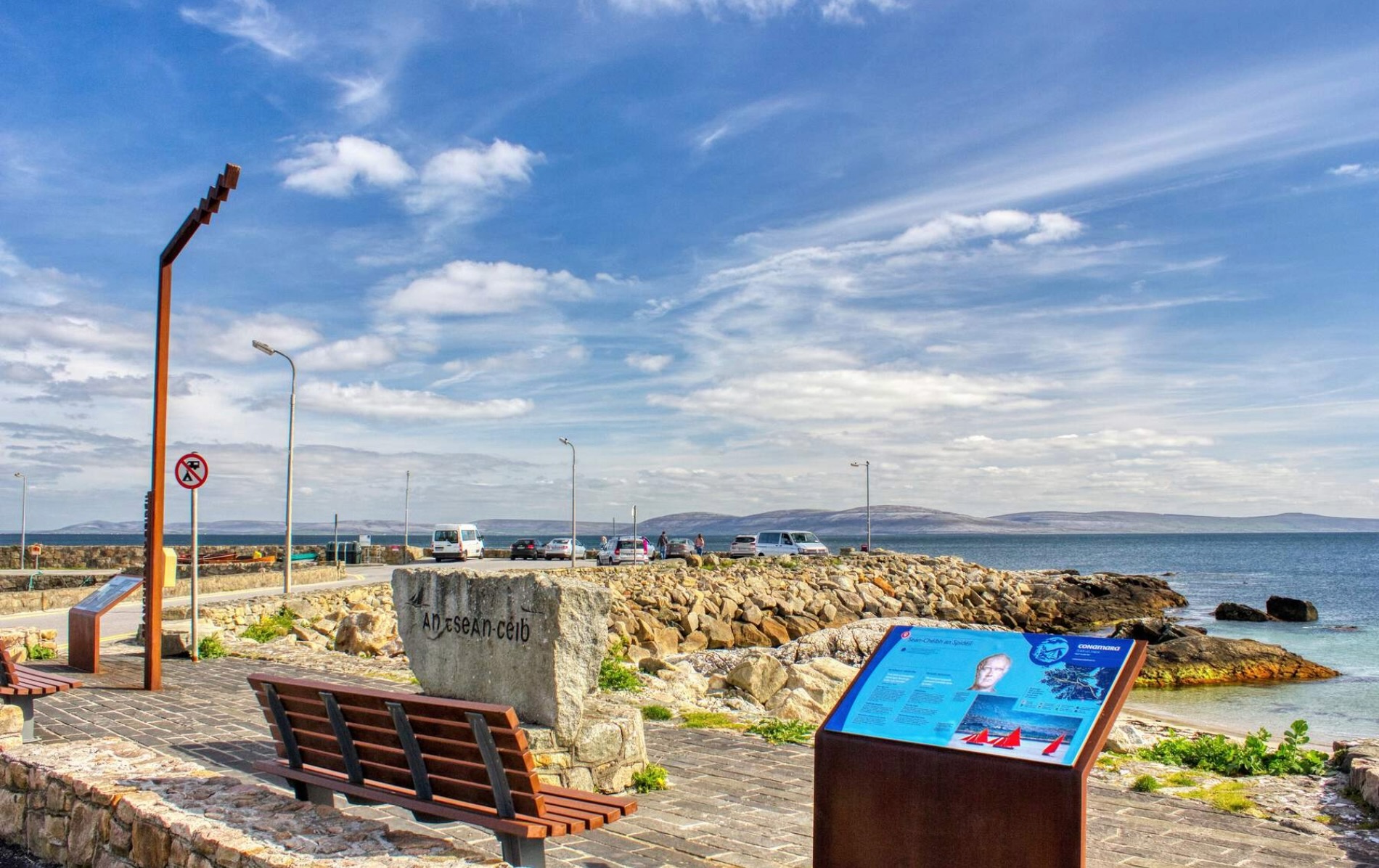 Seafront promenade in Spiddal village with information boards and views over Galway Bay.