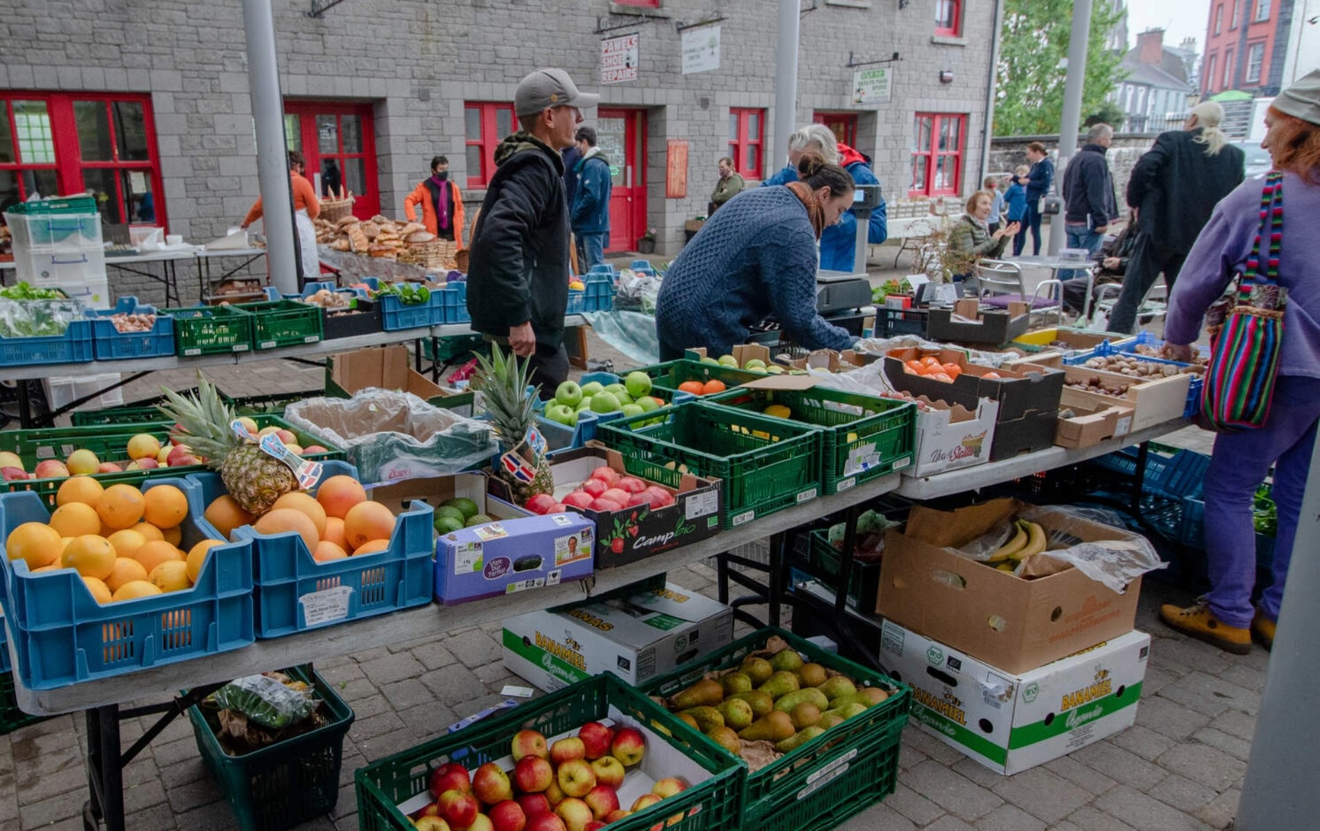 People browsing fresh fruit and vegetable stalls at Carrick-on-Shannon farmers market in County Leitrim.