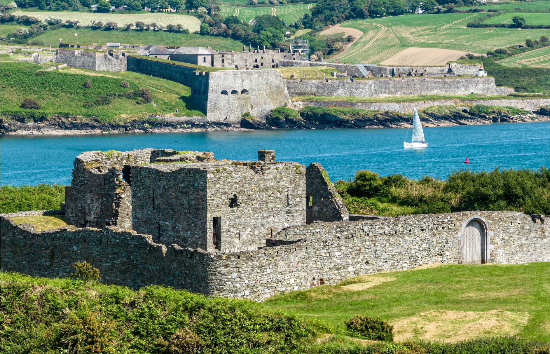 Stone ruins of James Fort face Charles Fort across Kinsale Harbour under bright summer skies in County Cork.