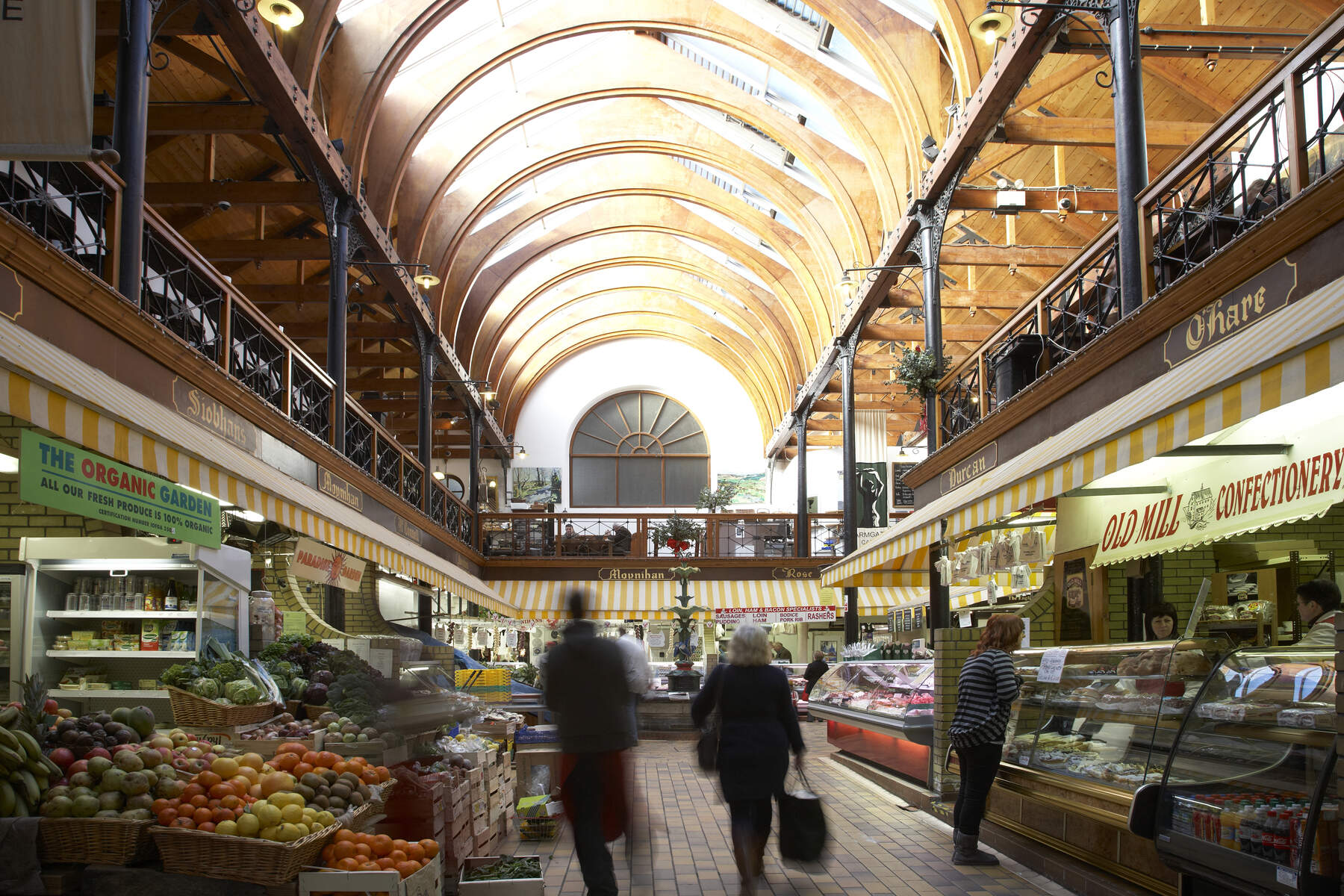 Shoppers browse fresh produce and artisan stalls beneath the vaulted wooden ceiling of the English Market in Cork.