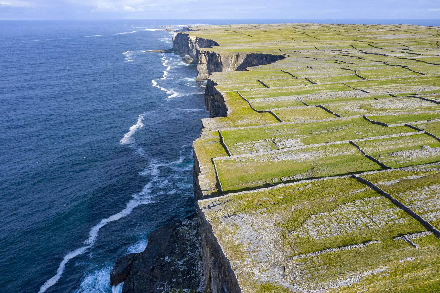 Aerial view of stone-walled fields stretching to dramatic sea cliffs on the Aran Islands, County Galway.