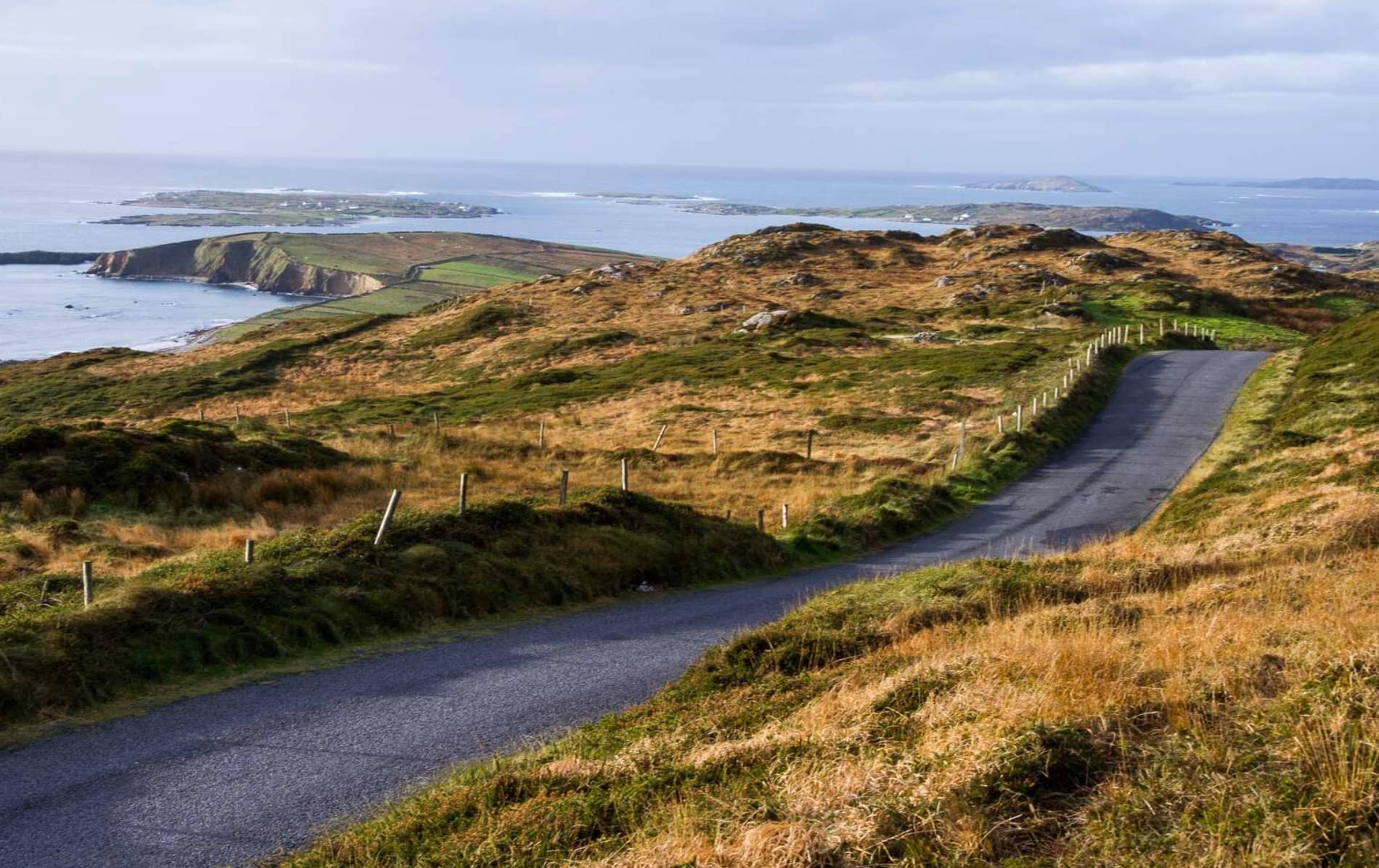 A winding road leads through the rolling hills of Sky Road, Clifden, Galway, with sweeping views of the Atlantic coastline.