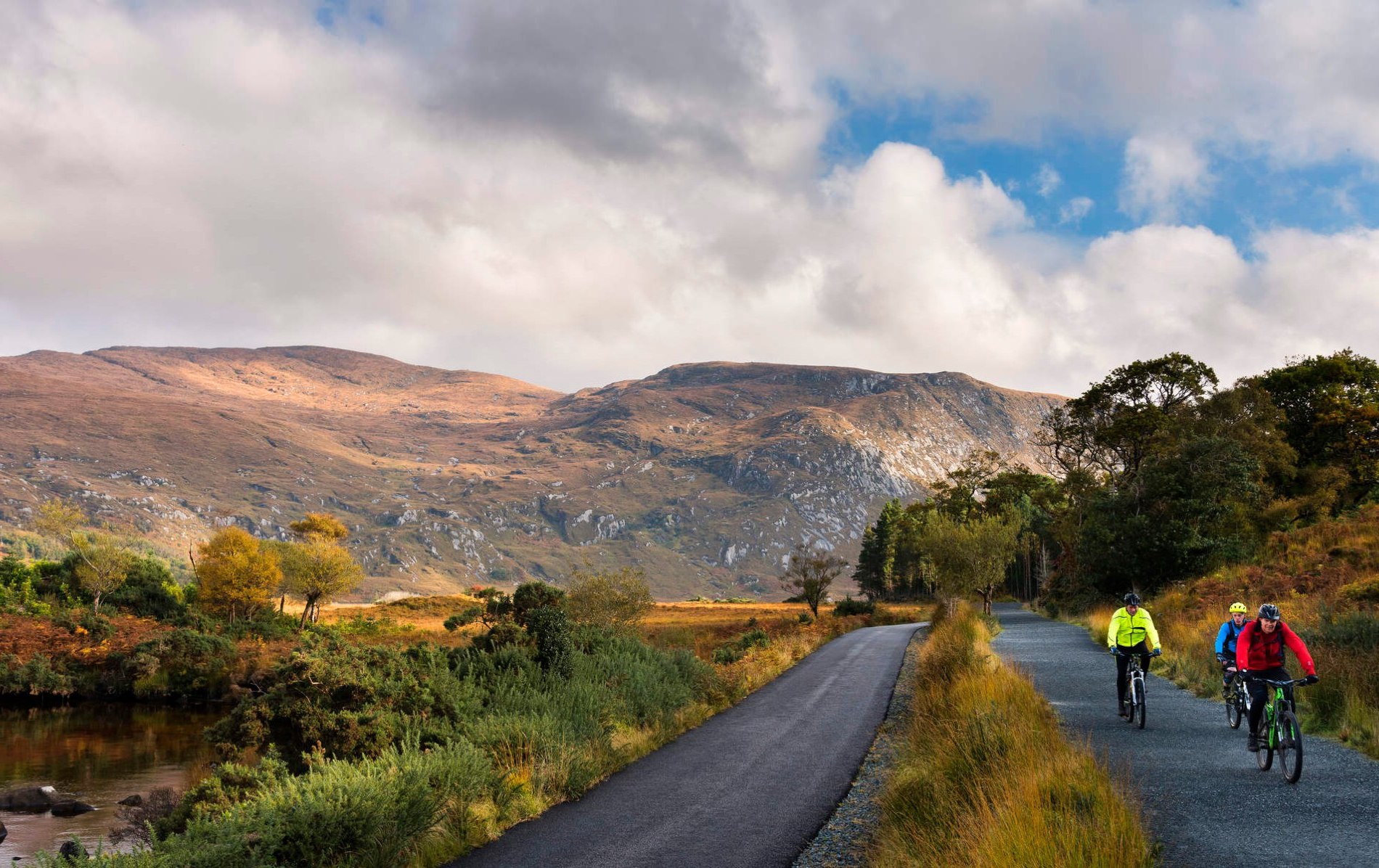 Scenic mountain road winds through Donegal’s northern headlands, with cyclists on a guided tour beneath a cloudy sky.