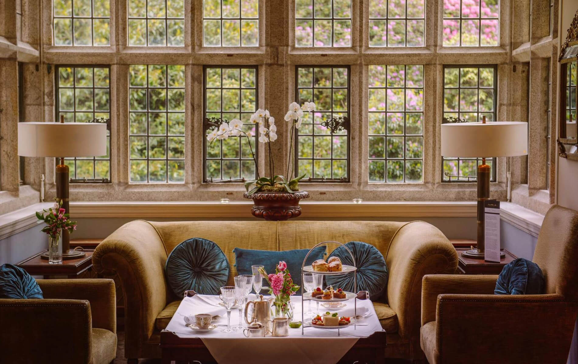 Afternoon tea is set in a plush lounge at Waterford Castle, framed by elegant leaded windows.