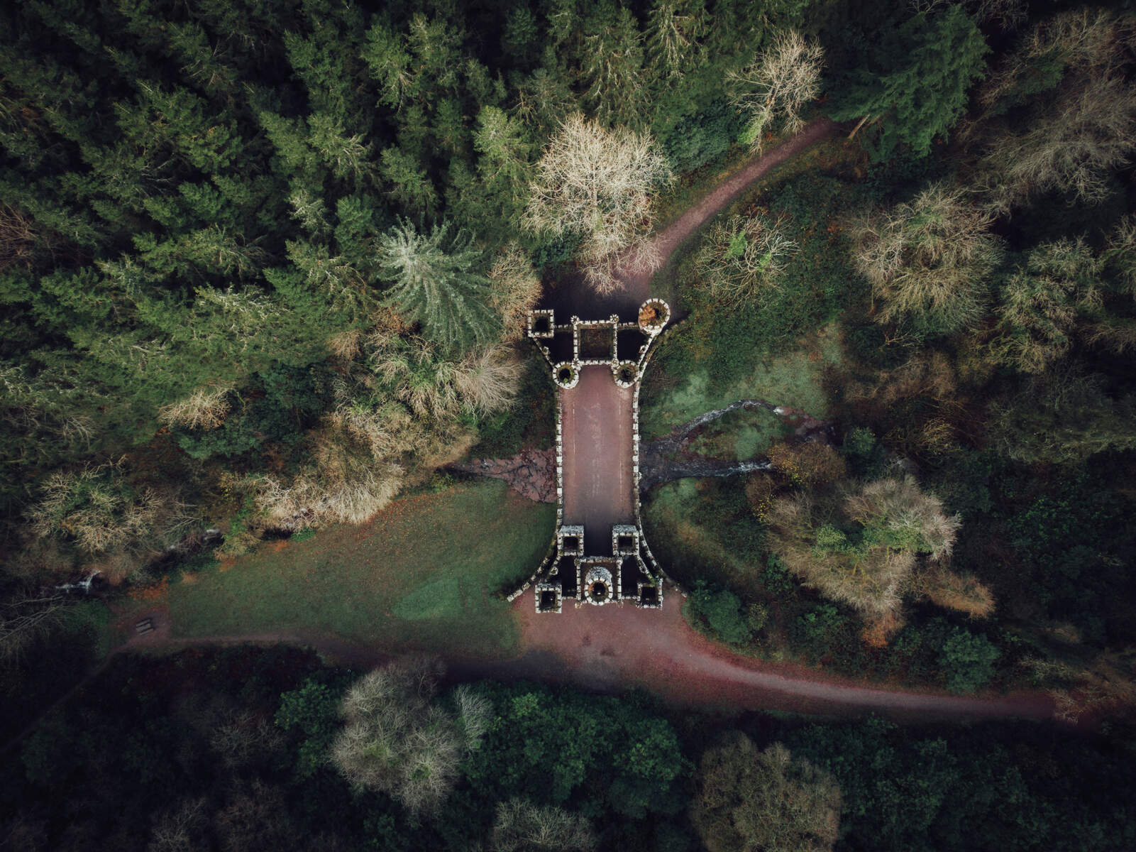 Aerial view of Ballysaggartmore Towers, Waterford, nestled among dense woodland and intersected by winding forest trails.