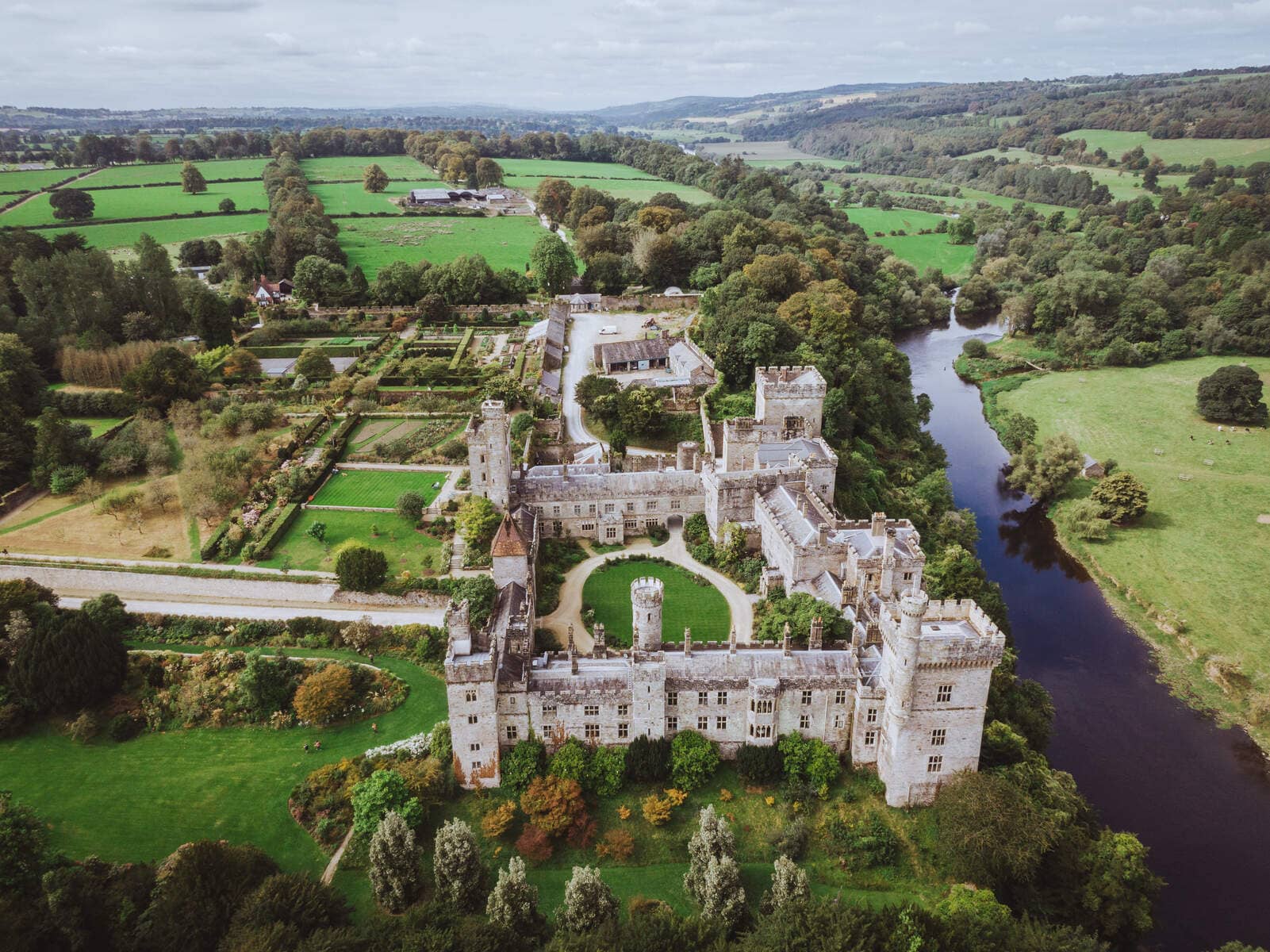 Aerial view of Lismore Castle and gardens surrounded by lush countryside and a winding river.