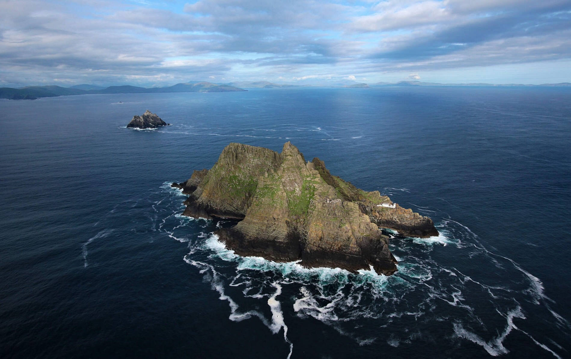 Aerial view of Skellig Michael’s jagged rock formation in County Kerry surrounded by deep blue Atlantic swells.