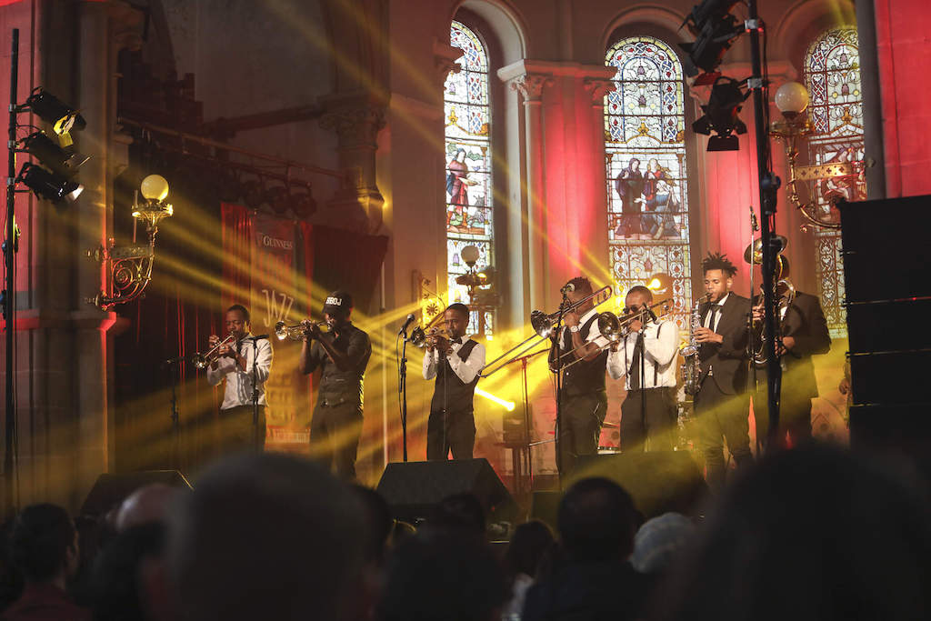 Brass band performing under stained glass windows at the Guinness Cork Jazz Festival.