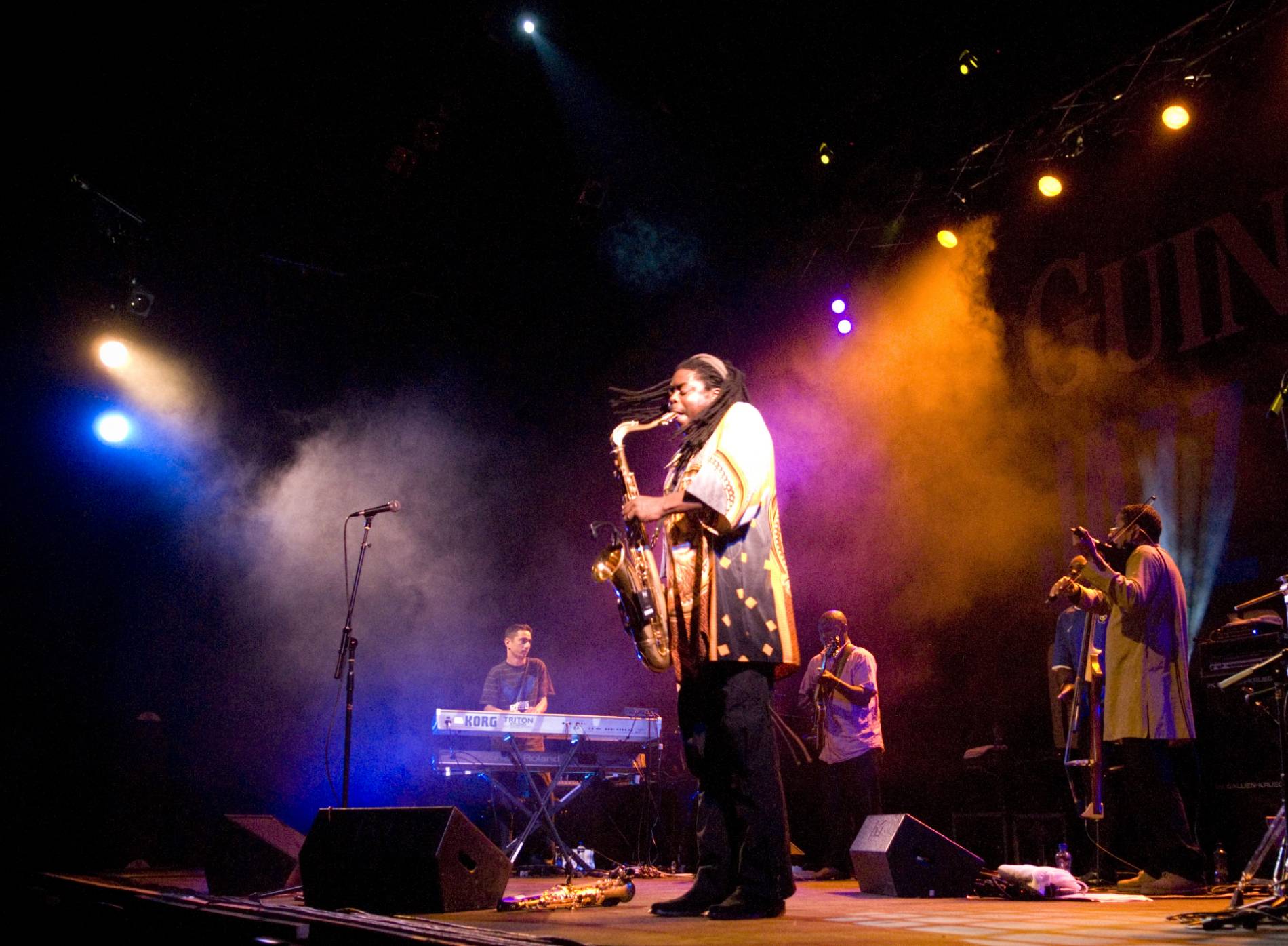 Saxophonist performs on smoke-filled stage at Cork Jazz Festival with band and vivid lighting.