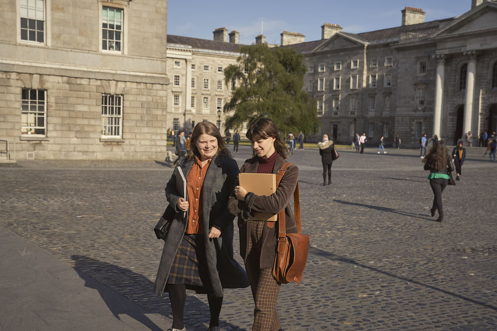 Students walk through cobbled Trinity College Dublin quad.