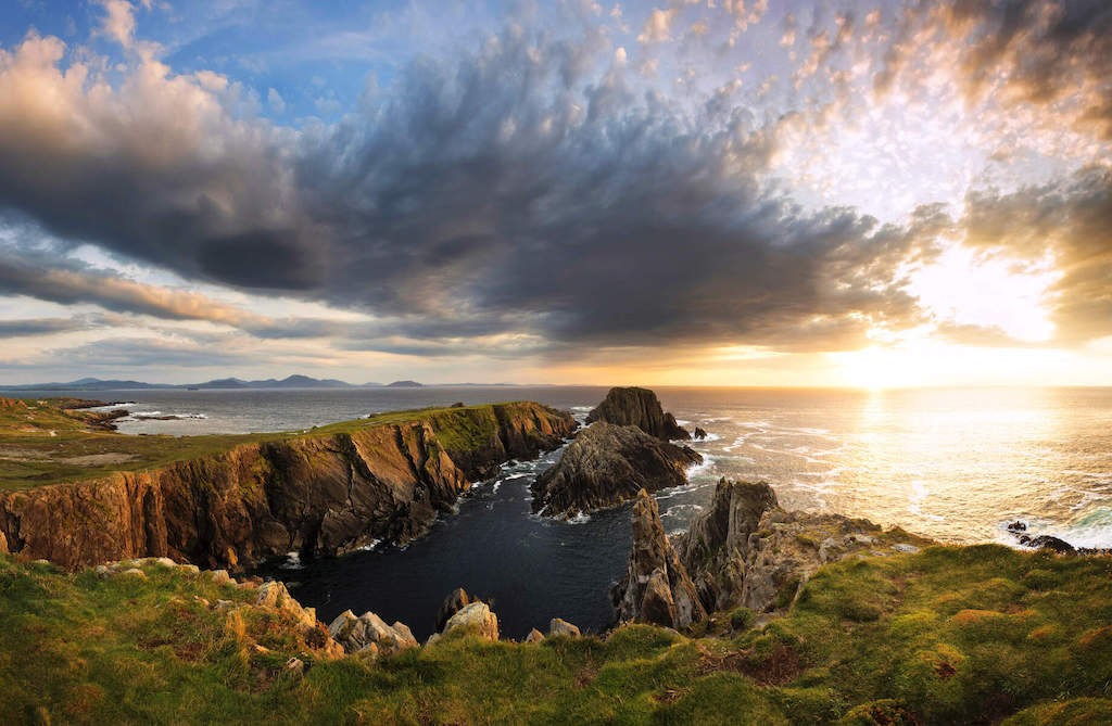 Cliffs at Malin Head lit by sunset glow under a dramatic sky on Ireland’s Wild Atlantic Way in Donegal.