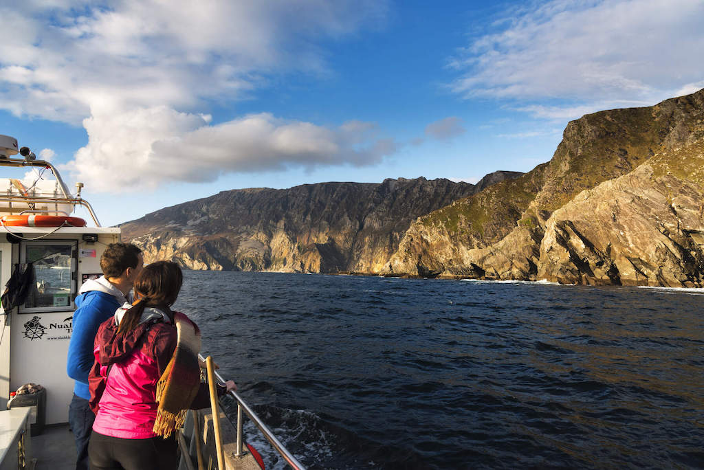 Couple on a boat tour gaze at the towering Slieve League cliffs, among the highest sea cliffs in Europe, in Donegal.