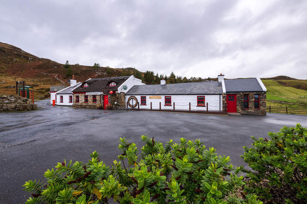 The Singing Pub with red doors set against rolling hills in rural Donegal.