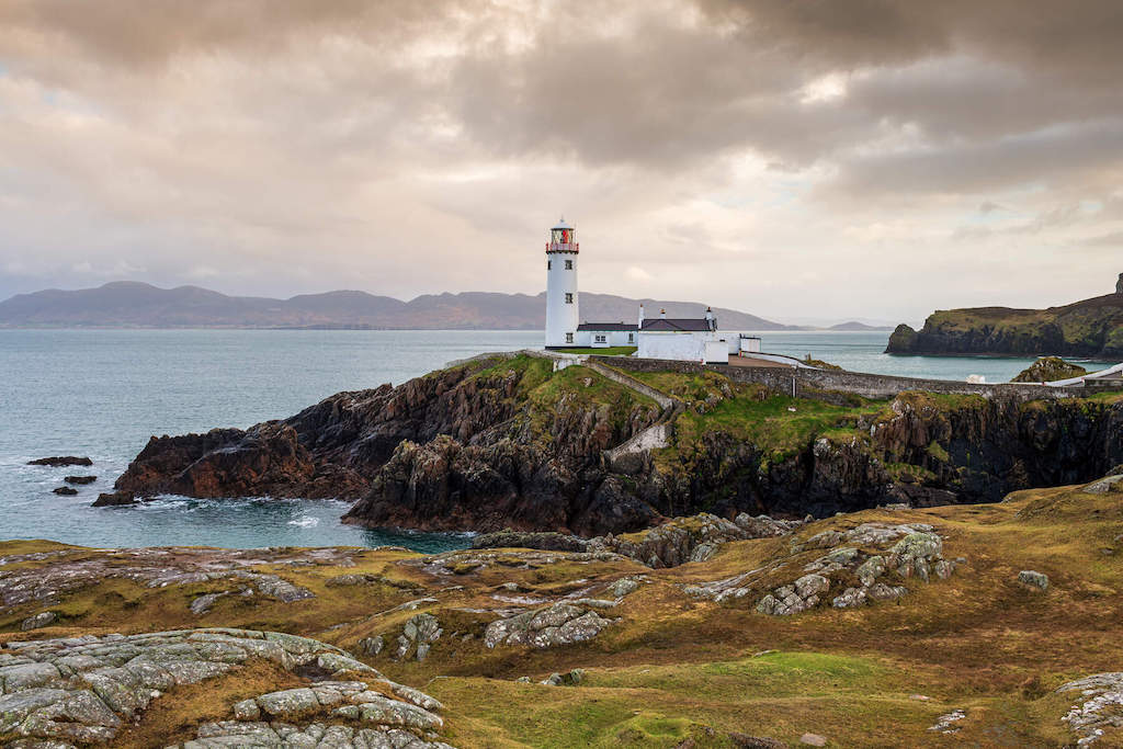 Fanad Head Lighthouse on a rocky Donegal coastline overlooking the Atlantic Ocean.