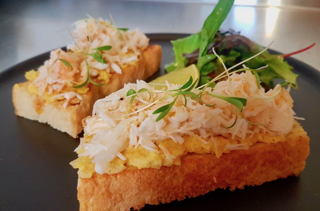 Crab on toast with scrambled eggs and salad, garnished with lime at Kealy's Seafood Bar, Donegal.