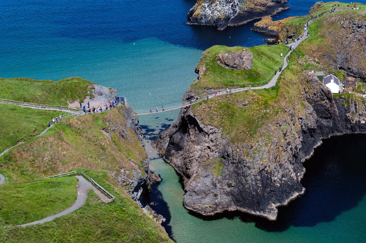 Visitors crossing Carrick-a-Rede Rope Bridge above the sea on the Causeway Coastal Route, County Antrim.