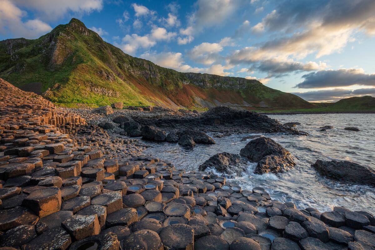 Basalt columns at the Giant's Causeway with cliffs rising behind, County Antrim.