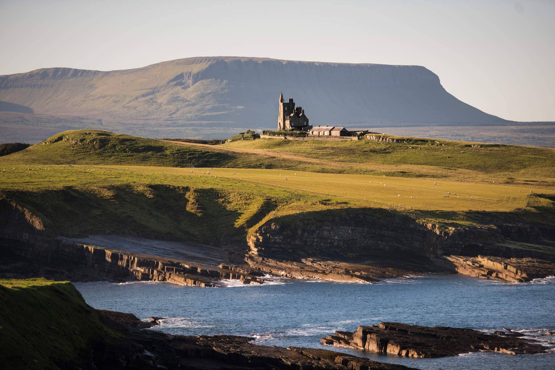 Classiebawn Castle on a grassy headland overlooking the sea with Ben Bulben in the background, County Sligo.