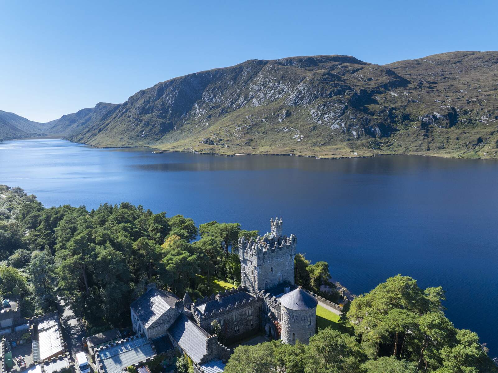 Glenveagh Castle by Lough Veagh, surrounded by trees and mountains in Glenveagh National Park, County Donegal.