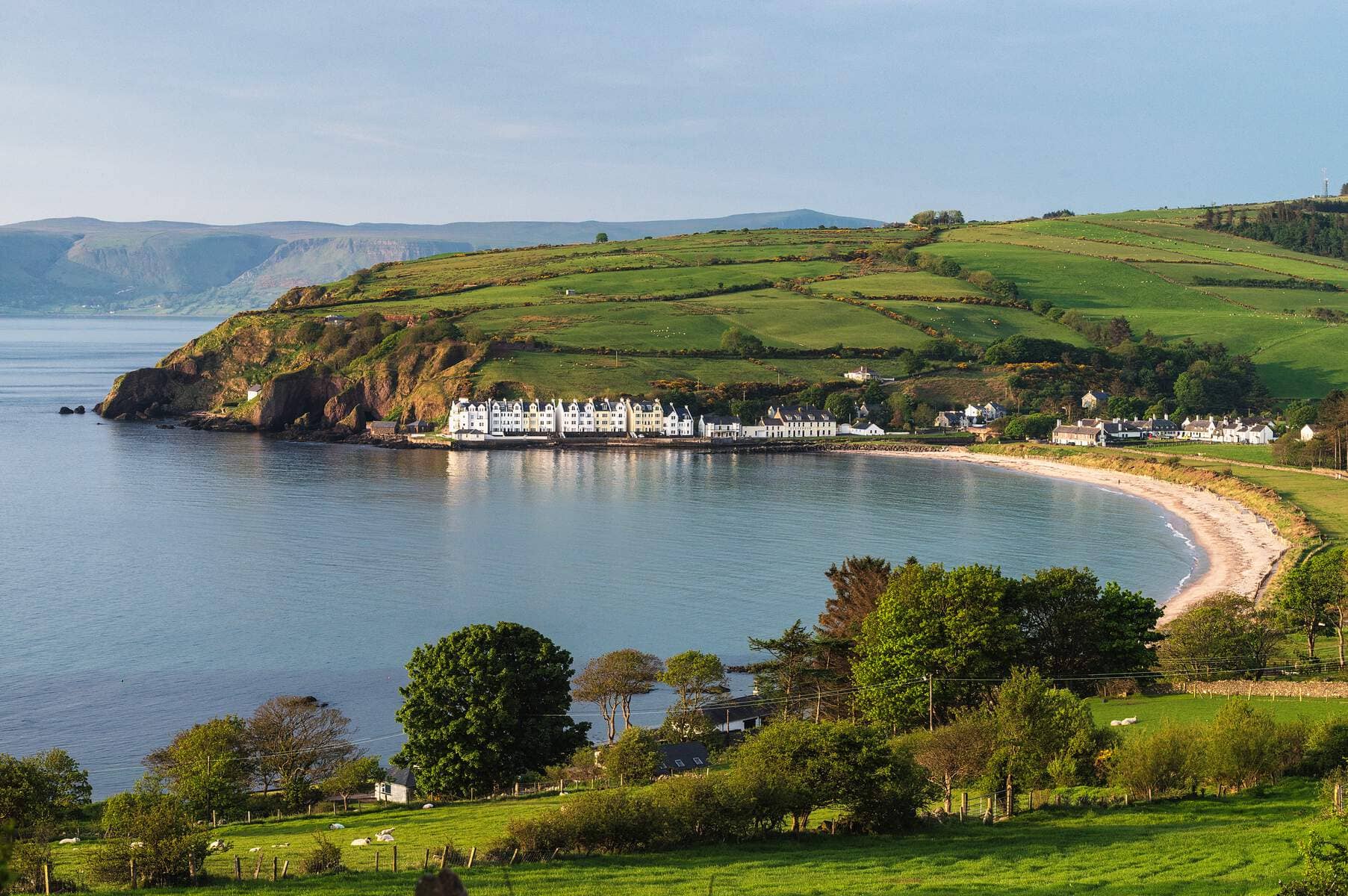 Coastal village of Cushendun and green hills seen from Torr Head Road in County Antrim.