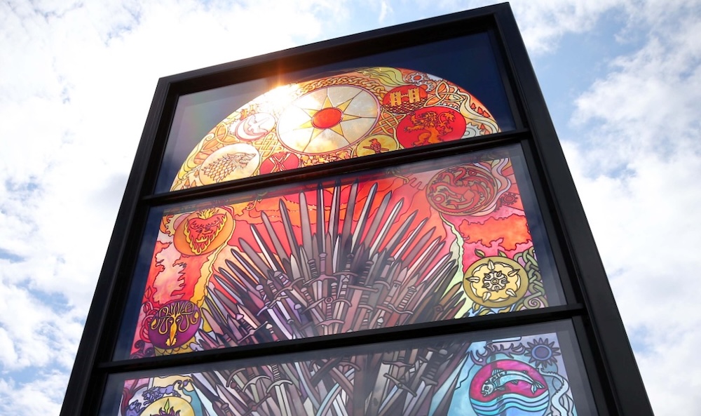 Stained-glass panel from Belfast’s Glass of Thrones trail depicting the Iron Throne surrounded by colourful house sigils.