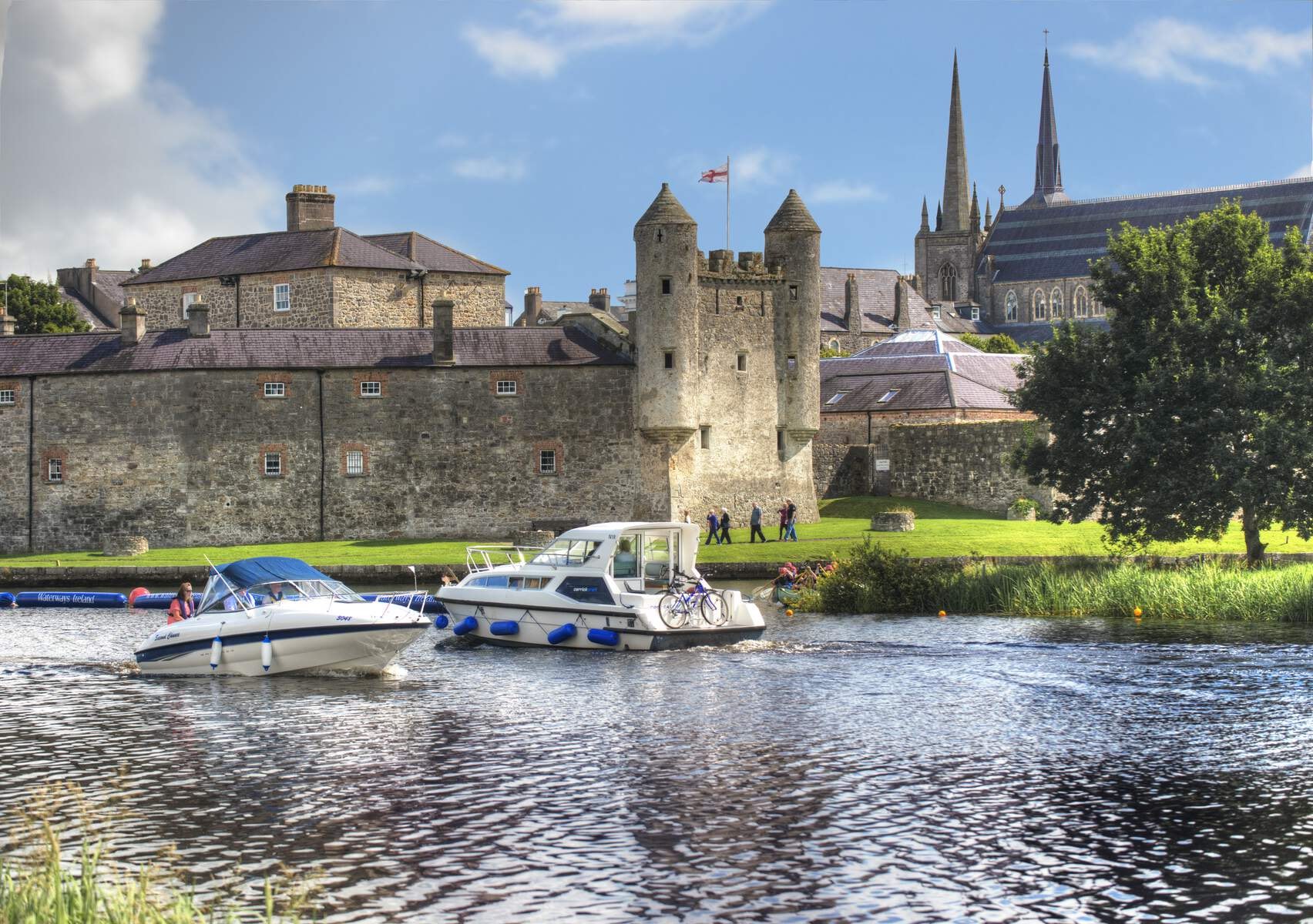 Two boats pass by one another on the River Erne with Enniskillen town in the background.
