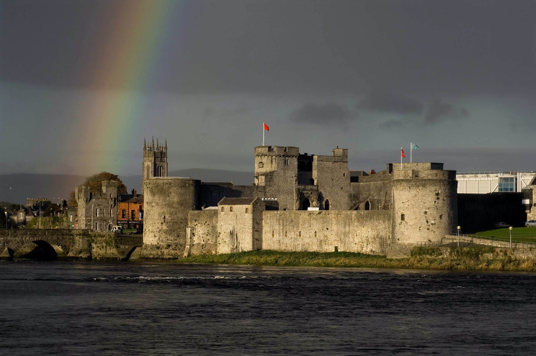 Rainbow arches over King John's Castle beside the River Shannon in Limerick city at sunset.
