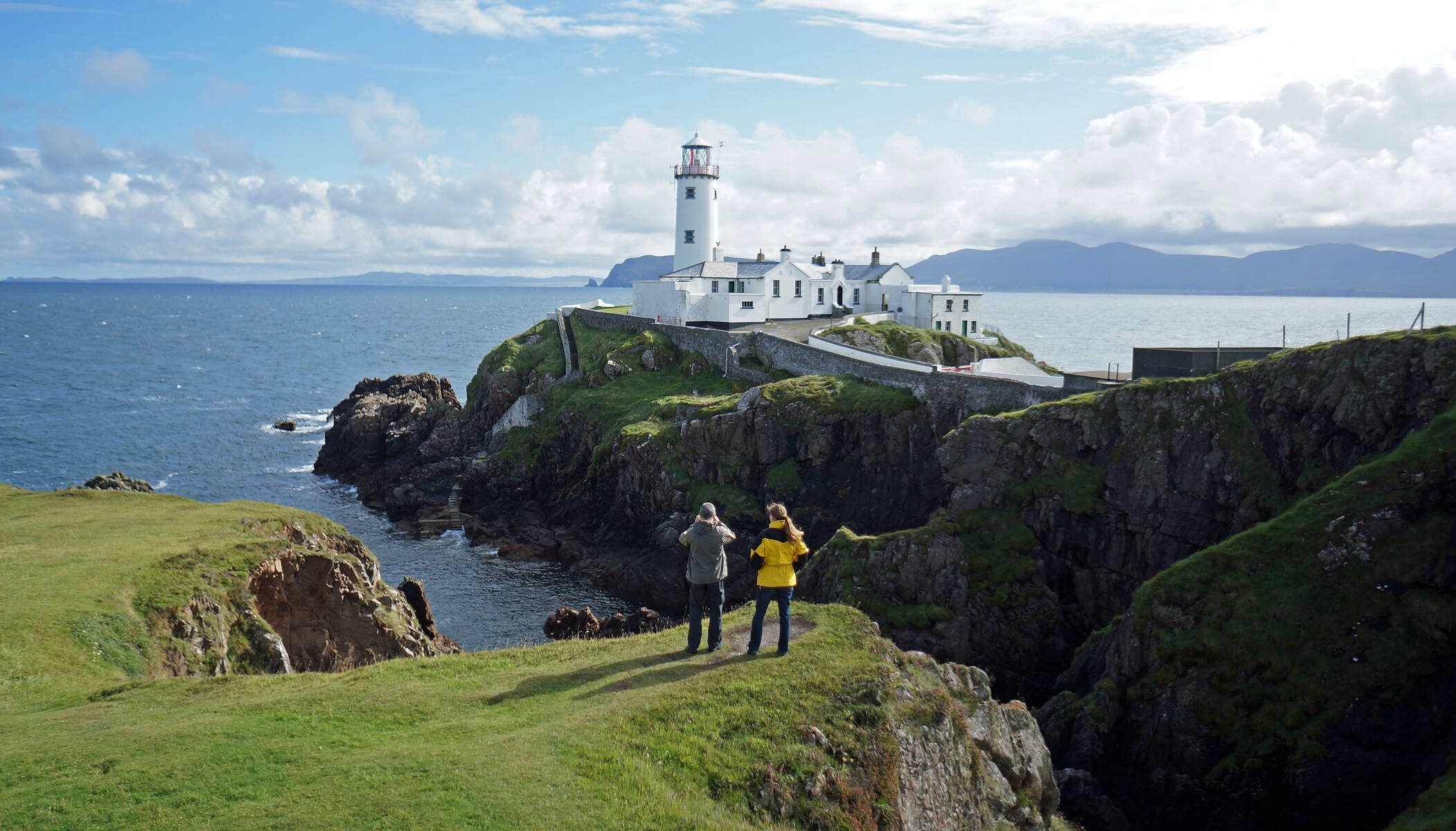Two people taking photos at Fanad Head Lighthouse on the Wild Atlantic Way, County Donegal.
