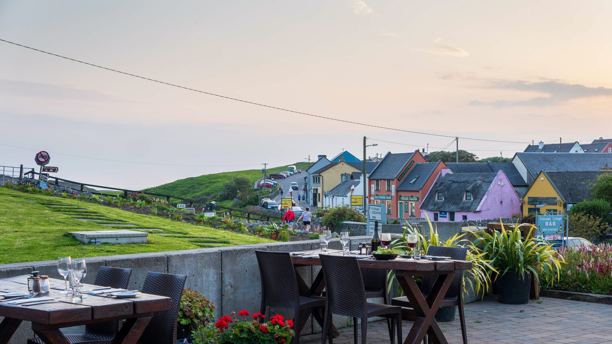 Outdoor dining area with set tables overlooking a colourful coastal street in Doolin, County Clare.