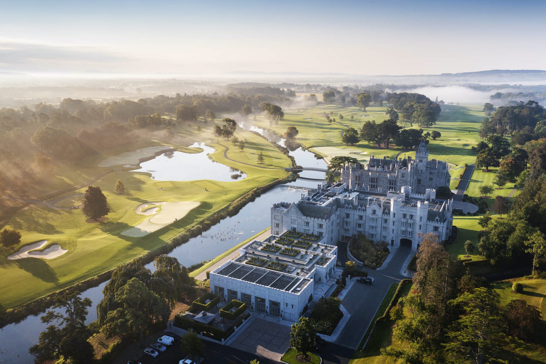 Aerial view of Adare Manor in County Limerick, a luxury castle estate with golf course and misty sunrise.