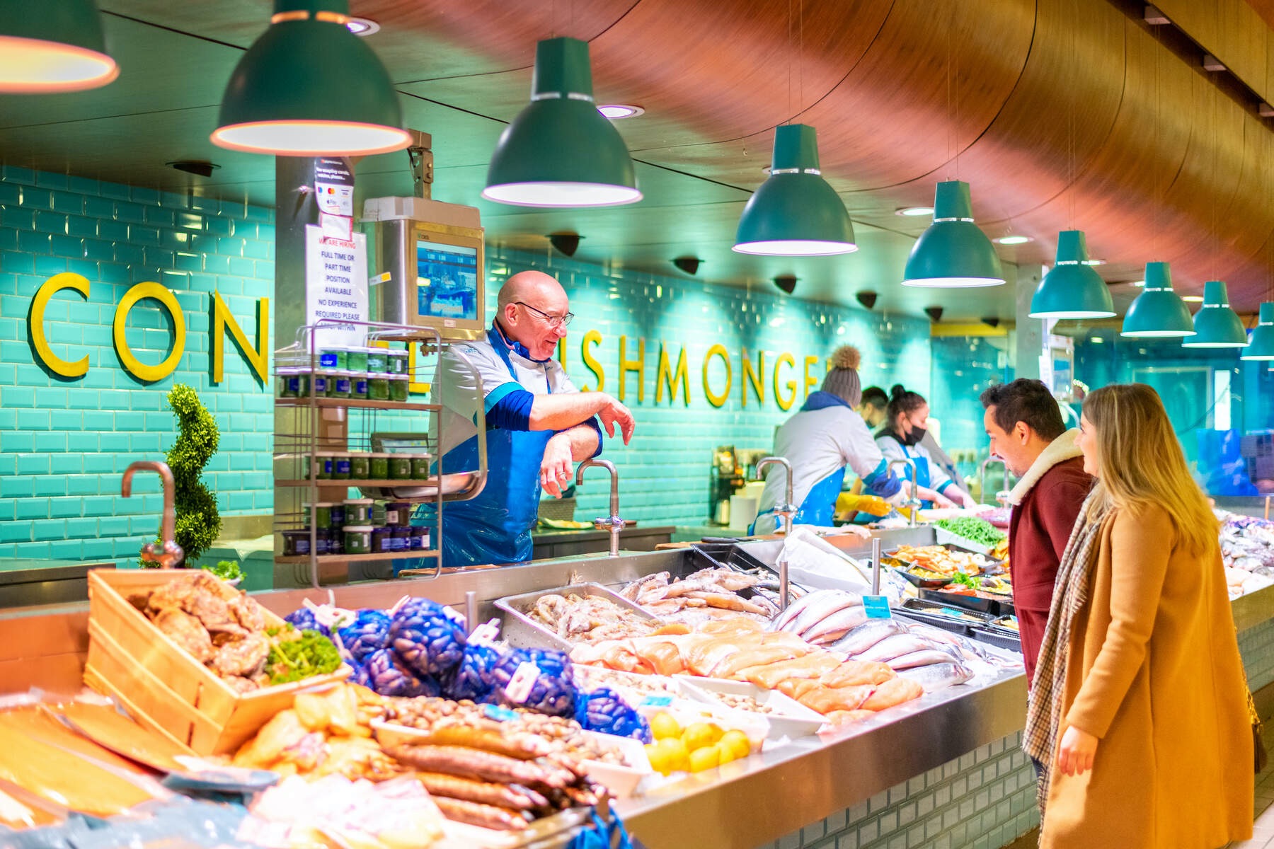 Fishmonger chatting to customers at a vibrant seafood stall in the English Market in Cork city.