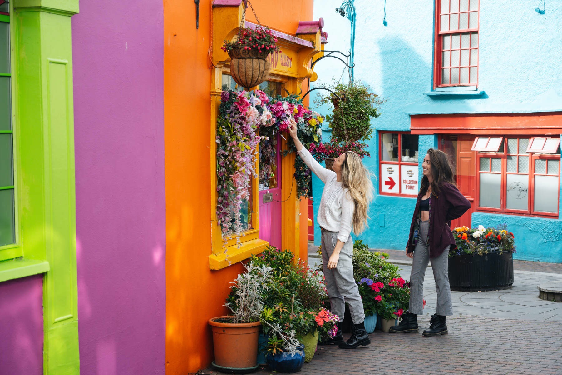 Two women admiring flowers outside a colourful shopfront in Kinsale, County Cork.