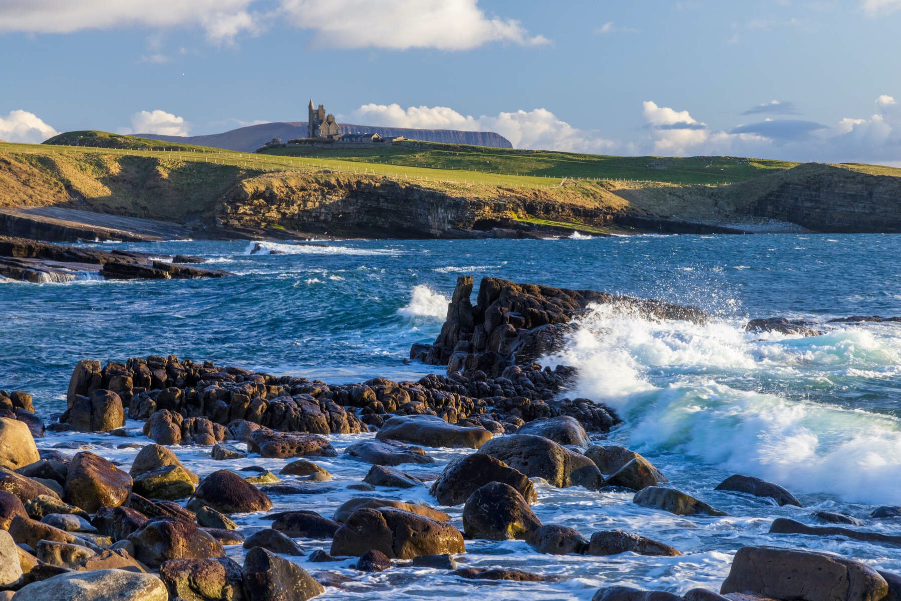 Coastal waves crashing on rocks near Classiebawn Castle in County Sligo.