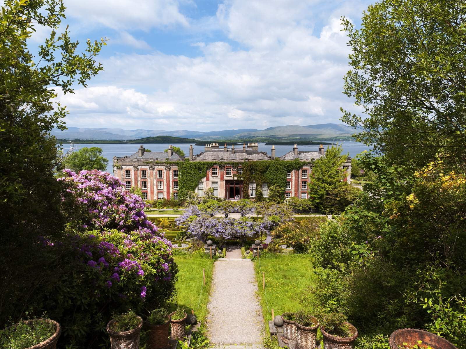 Grand ivy-covered Bantry House with formal gardens against a backdrop of sea and mountain views in Cork.