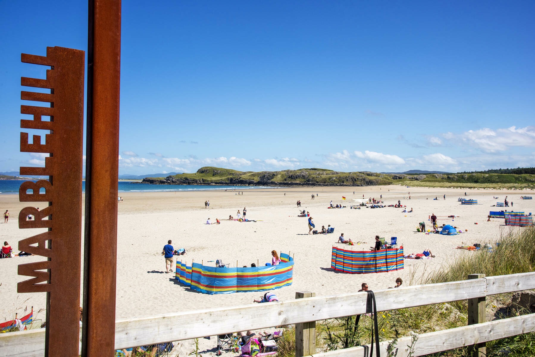 Families relaxing on the sandy beach at Marble Hill in County Donegal on a sunny day.