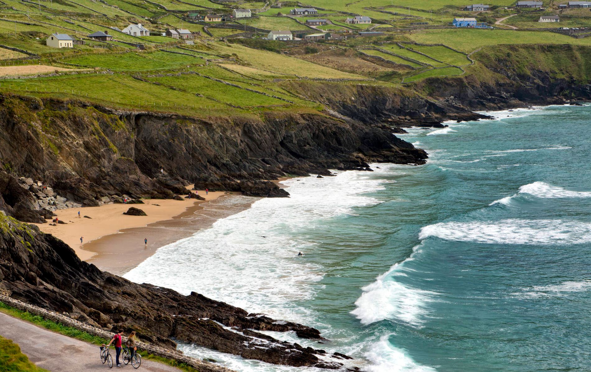 Waves lapping against the shore at Coumeenoole Beach on the Dingle Peninsula in County Kerry, with cottages perched on cliffs.