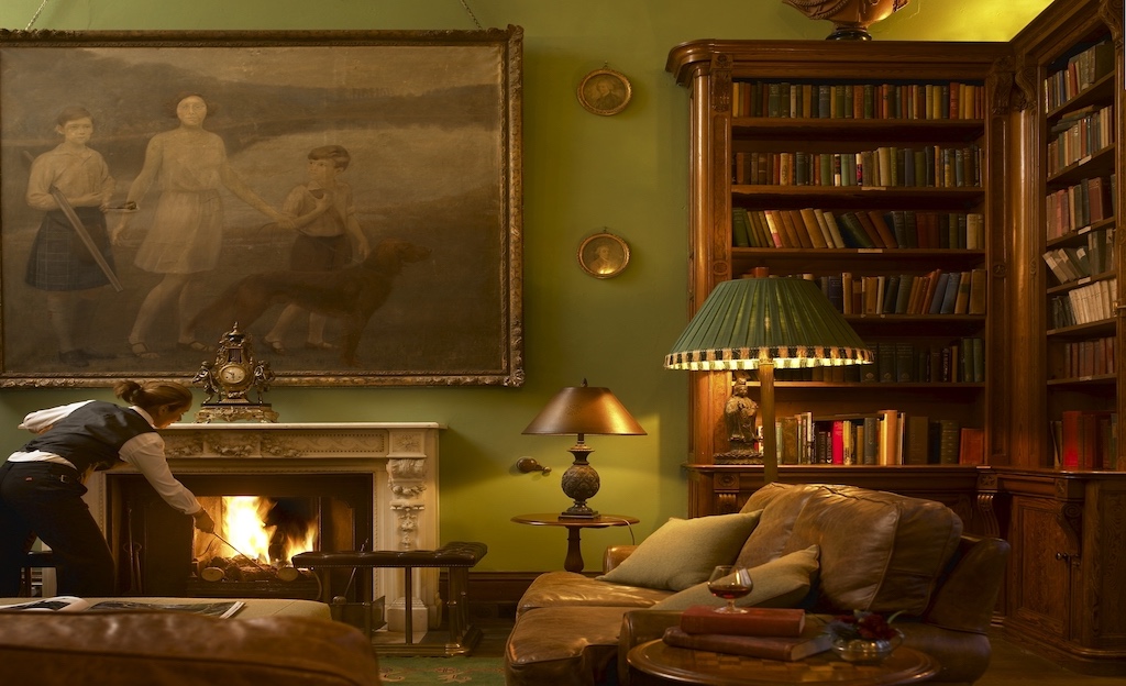 Elegant library with a crackling fire, large portrait and leather armchairs at Castle Leslie Estate, County Monaghan.